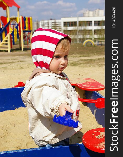 The girl plays sand on a children's playground