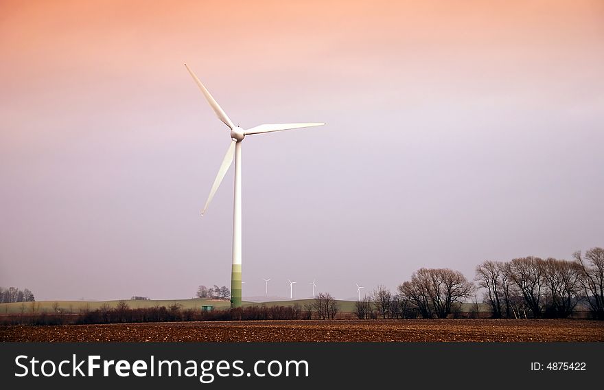 Wind turbines in movement during the sunset in the fields