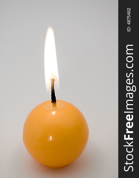 Small yellow burning candle, grey background. Small yellow burning candle, grey background