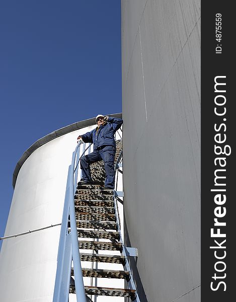 Engineer talking in phone on stair of large fuel storage tank. Engineer talking in phone on stair of large fuel storage tank