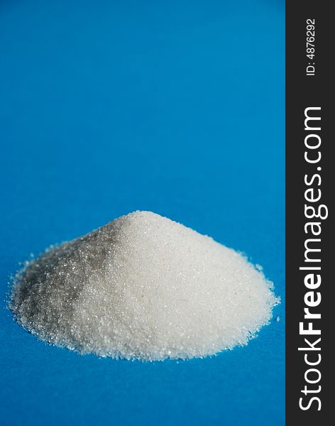 Heap of white sugar on a blue background