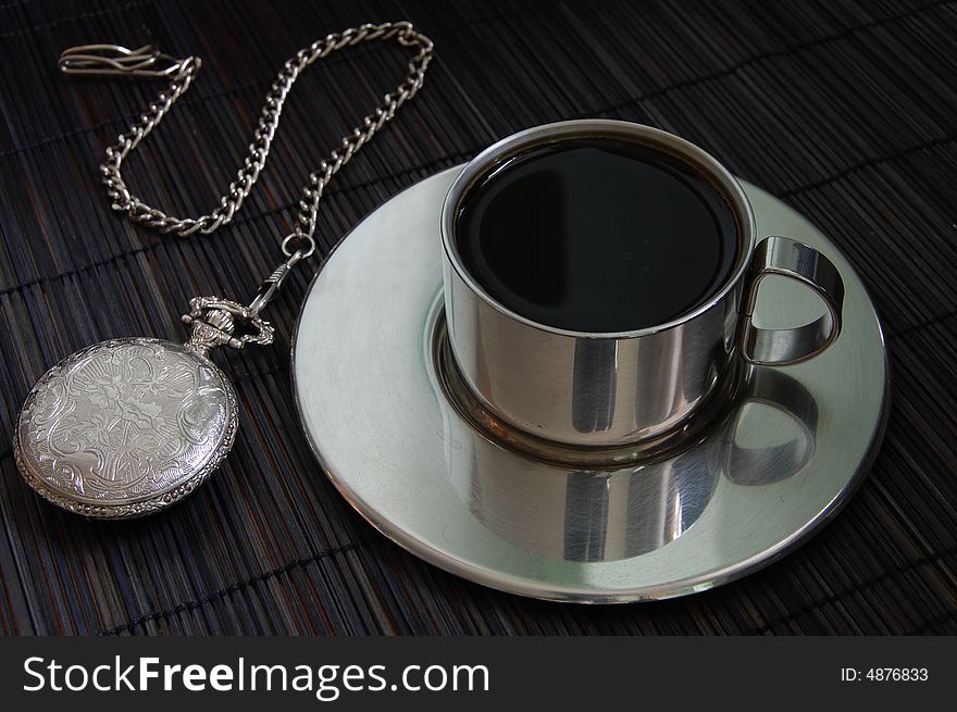 Watch and coffee on a black bamboo table.