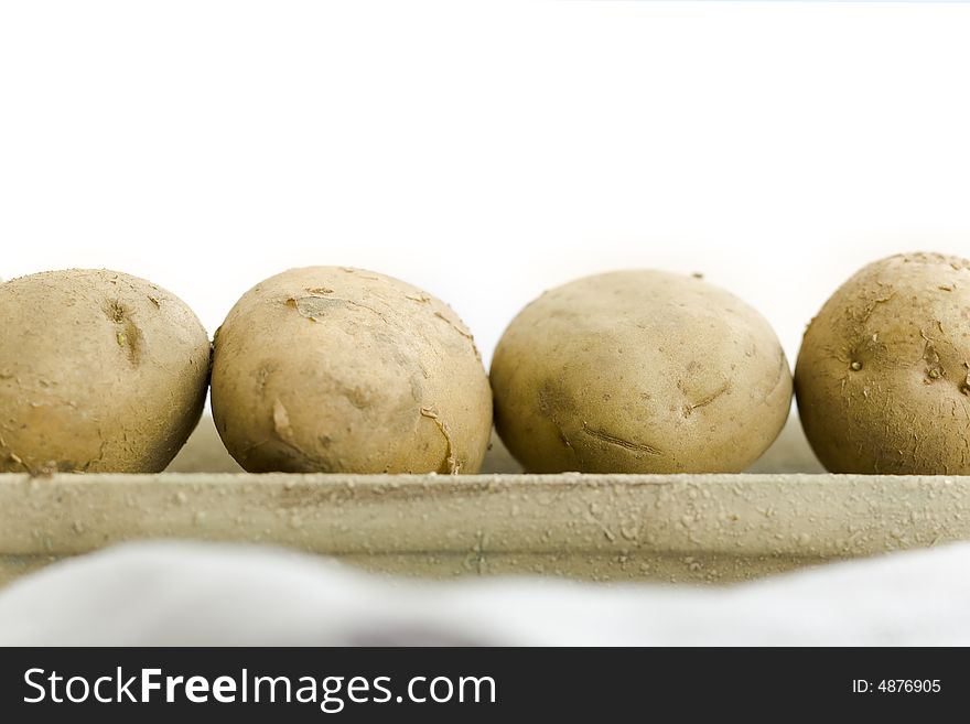 Five raw potatoes on the vase on the table