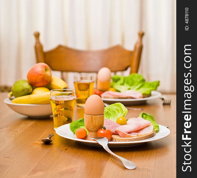 Table served with snacks. Fruits, vegetables, bread, egg, ham etc. Focus on the front egg, shallow depth of field. Table served with snacks. Fruits, vegetables, bread, egg, ham etc. Focus on the front egg, shallow depth of field.