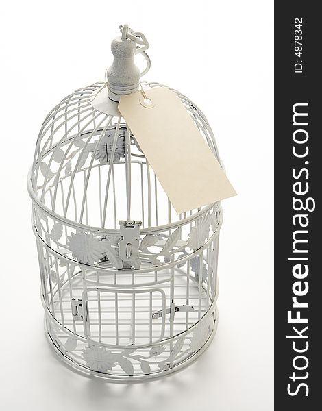 White birdcage with cream sale tag tied to the top. White birdcage with cream sale tag tied to the top.