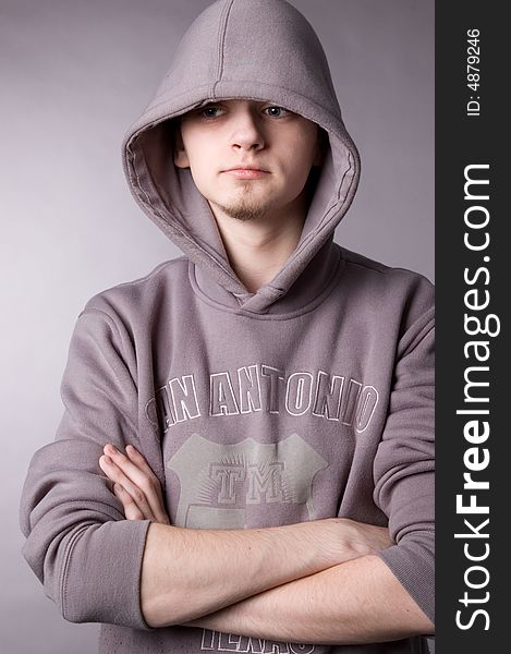 The young guy in a hood in studio on a grey background