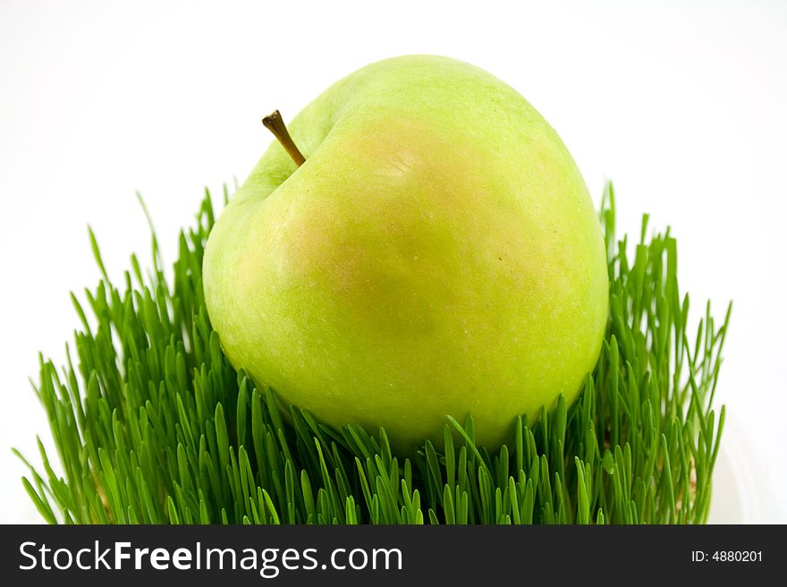 Green apple on grass isolated onwhite