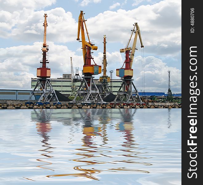 Container cranes for loading and unloading ships. Reflection over water.