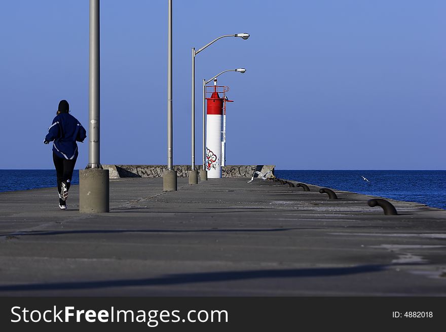 Runner jogging to the end of a concrete pier. Runner jogging to the end of a concrete pier.