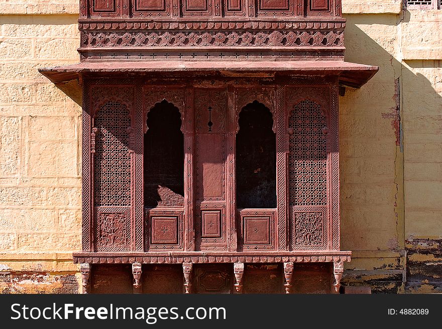 India, Jaisalmer: Indian palace architecture; red walls and wooden carved frame and window