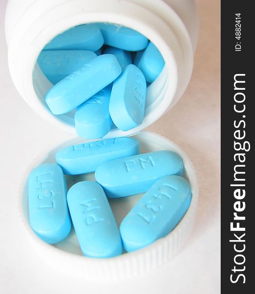 Blue generic pills pouring out of a bottle. Blue generic pills pouring out of a bottle