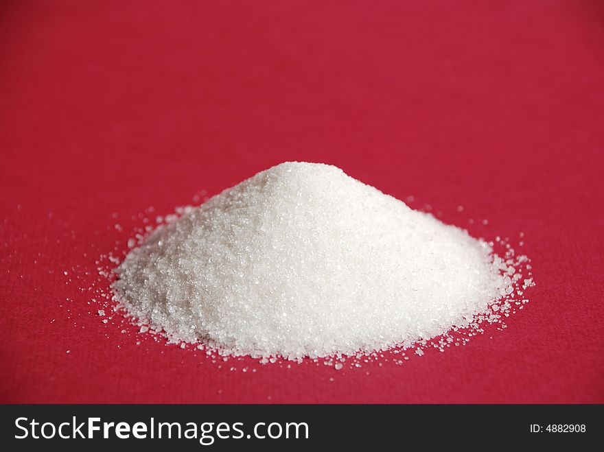 Heap of white sugar on a red background