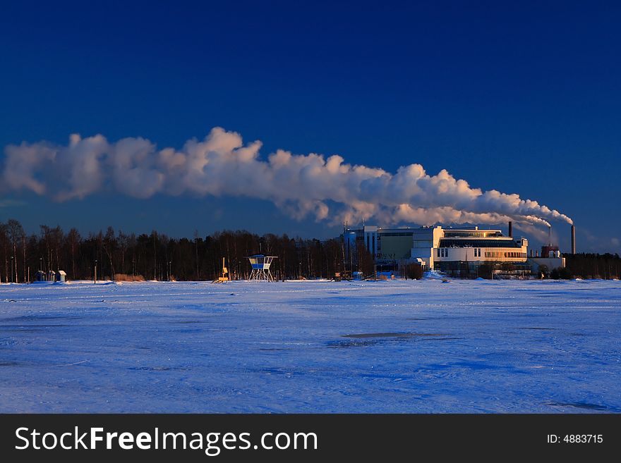 Factory smoke on blue sky in winter sunset