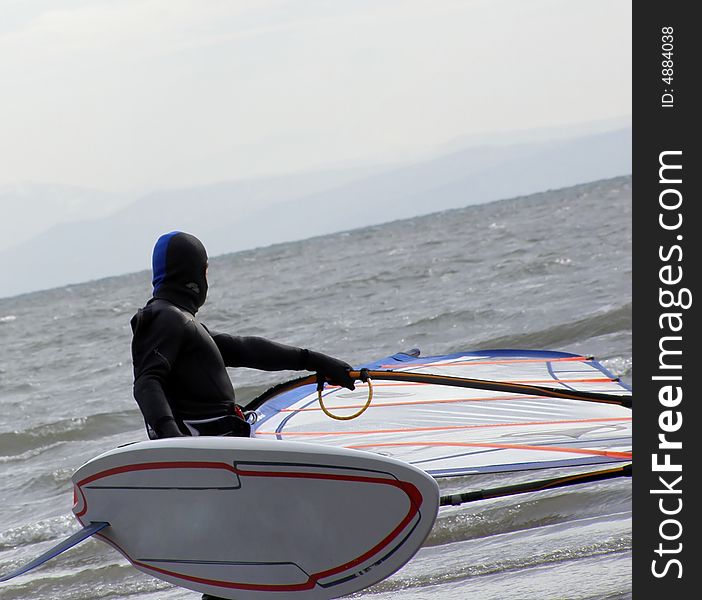 Windsurfer going in the water, winter scene background