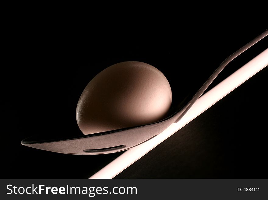 Egg on black plastic spoon with slits on black background. Egg on black plastic spoon with slits on black background.