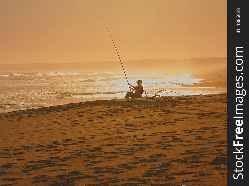 Fisherman' Rod with pulley on sand on beach with waves. Fisherman' Rod with pulley on sand on beach with waves