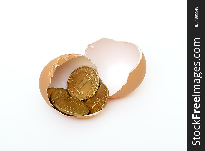 Coins lie in an egg-shell on white background. Coins lie in an egg-shell on white background