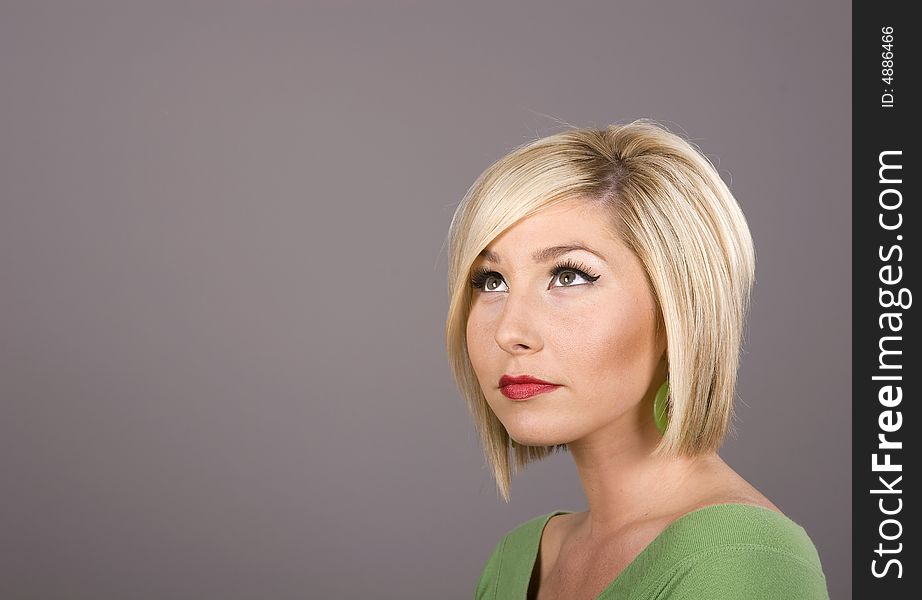 A blonde model in green blouse looking up and to the side. A blonde model in green blouse looking up and to the side