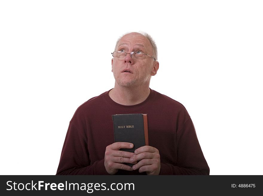 An older bald man with glasses holding a bible and looking to heaven. An older bald man with glasses holding a bible and looking to heaven