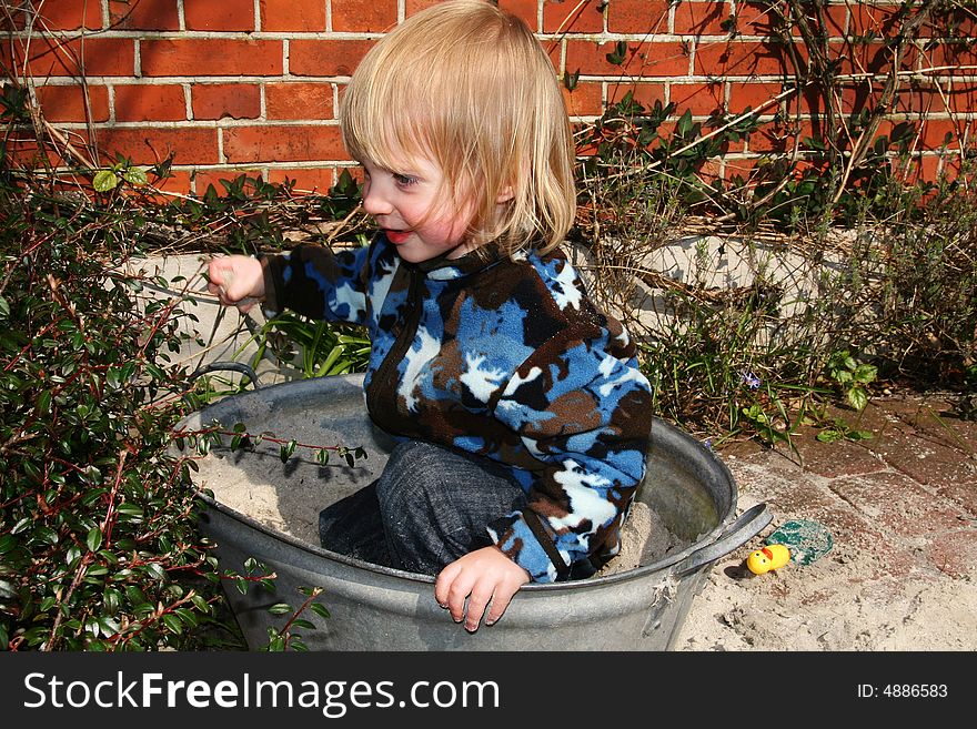 Child or toddler playing with sand in sandbox or sandpit. Child or toddler playing with sand in sandbox or sandpit