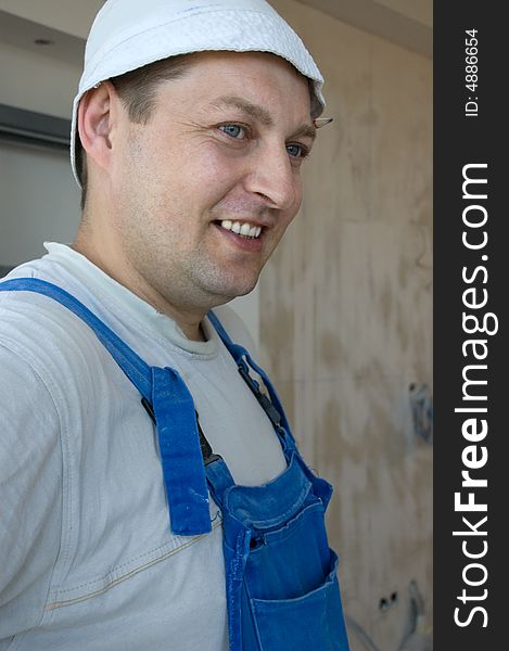 Smiling builder wearing a hat and a blue coverall