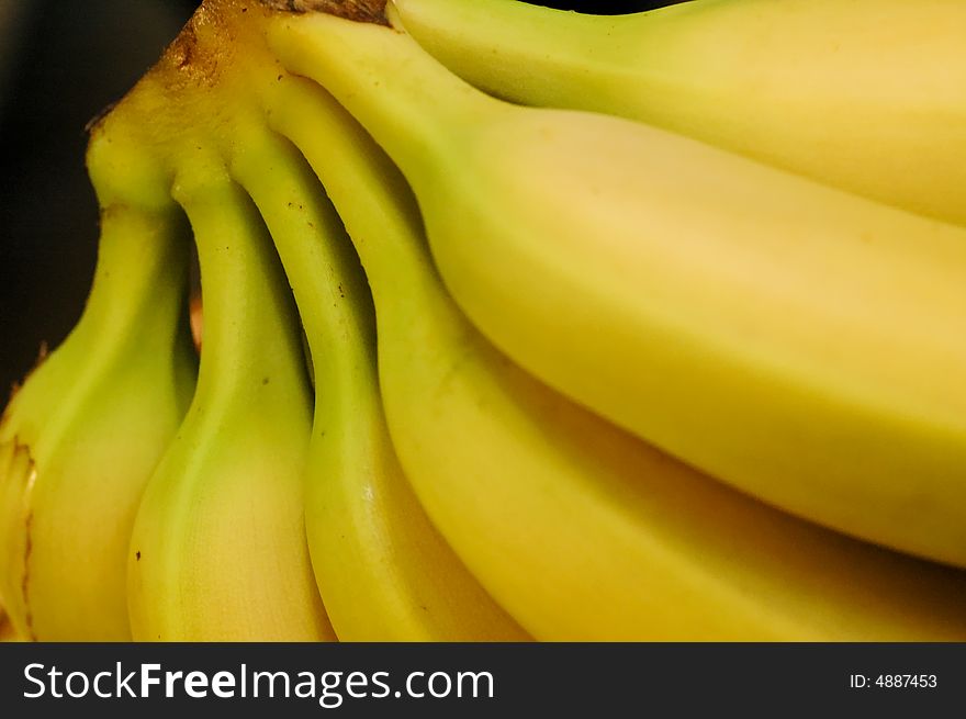 A bunch of yellow bananas against a black background. A bunch of yellow bananas against a black background.