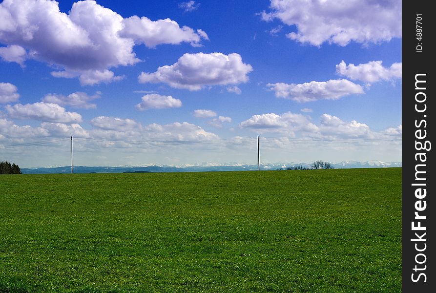Green gras with clouds and the alps in background. Green gras with clouds and the alps in background