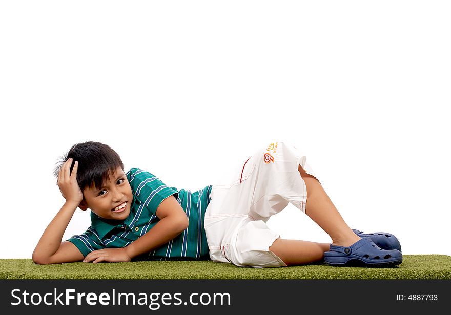 Cheerful child lying on a grass over a white background
