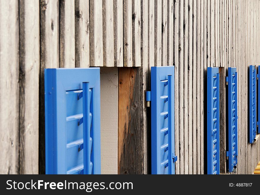 Wooden side of a hose with blue windows frames