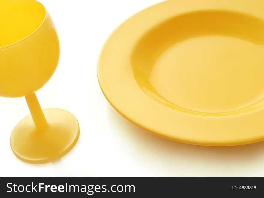 A place setting with yellow ceramic plate and yellow wineglass