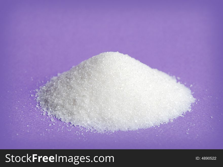Heap of white sugar on a violet background