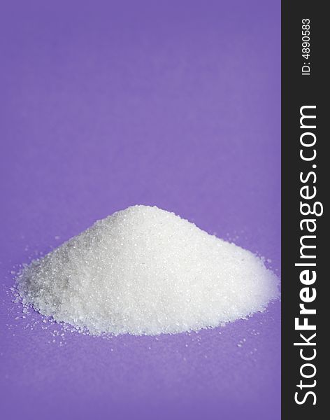 Heap of white sugar on a violet background