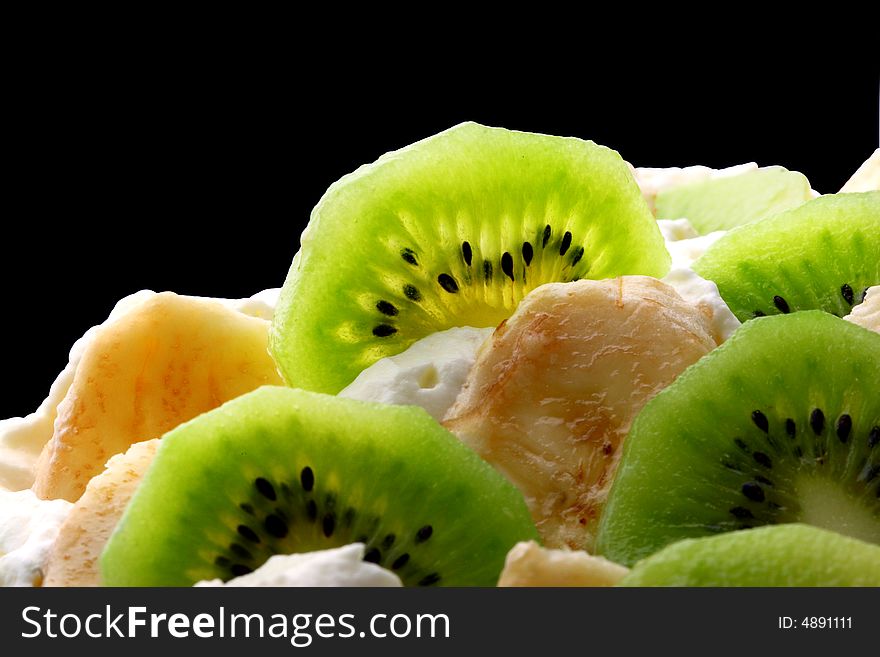 Top layer of pavlova cake with banana and kiwi close up over black