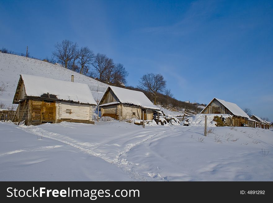 Winter landscape with the image of several old izbas about a snow-covered hill