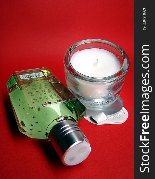 Green shampoo and white candle on red background. Green shampoo and white candle on red background