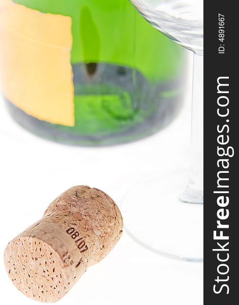 The bottle cork lays near to a bottle and a glass. The bottle cork lays near to a bottle and a glass