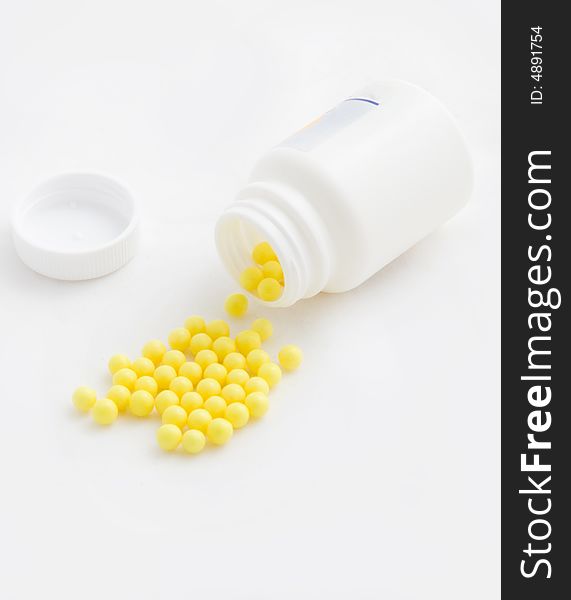 Yellow medicines were scattered from a white jar. Yellow medicines were scattered from a white jar