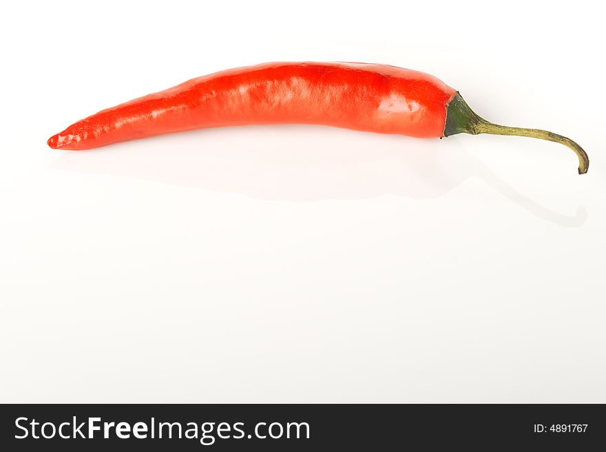 Isolated on white red hot chili pepper laying on the smooth surface with reflection. Isolated on white red hot chili pepper laying on the smooth surface with reflection