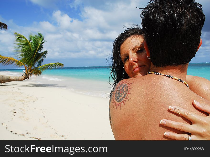 Woman hugging a man while peering over his shoulder in a tropical location. Woman hugging a man while peering over his shoulder in a tropical location.
