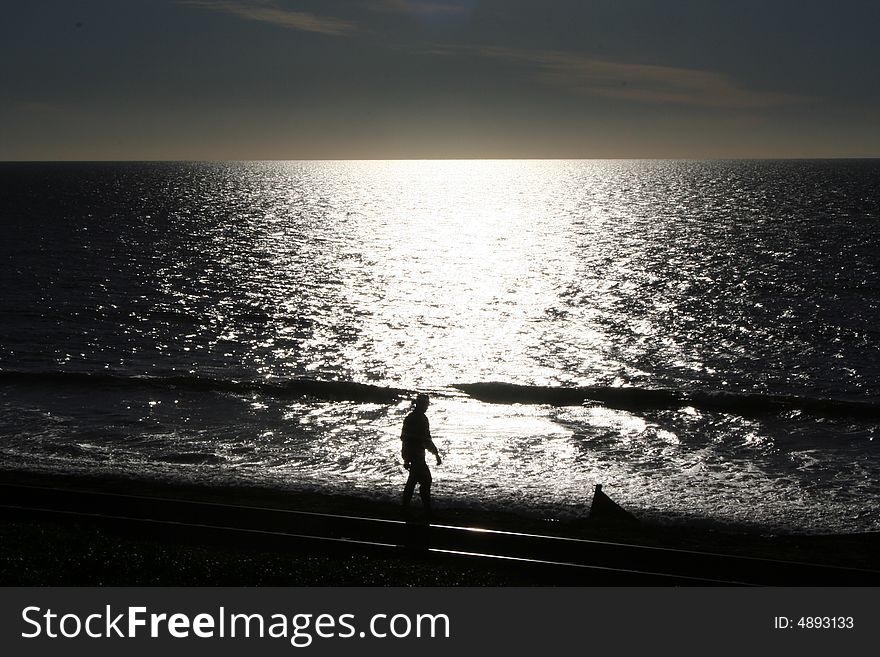Man walking on beach at sunset. Man walking on beach at sunset.