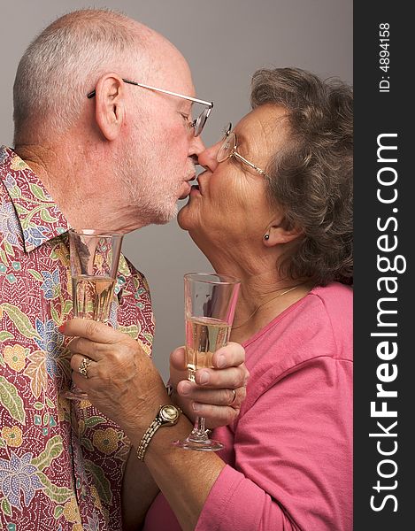 Happy Senior Couple Kissing while holding Champagne glasses.