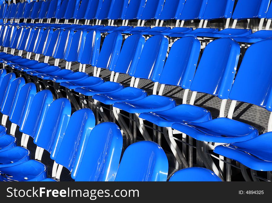 Several rows of blue plastic stadium seats