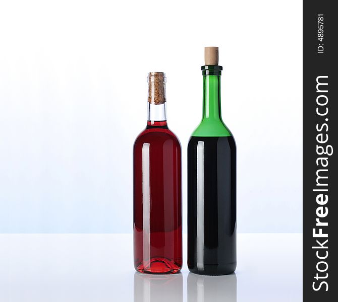 Two bottles of wine on white surface