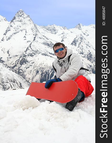 Happy man with red snowboard in mountains. Happy man with red snowboard in mountains