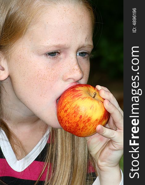 A white caucasian girl eating an apple. A white caucasian girl eating an apple