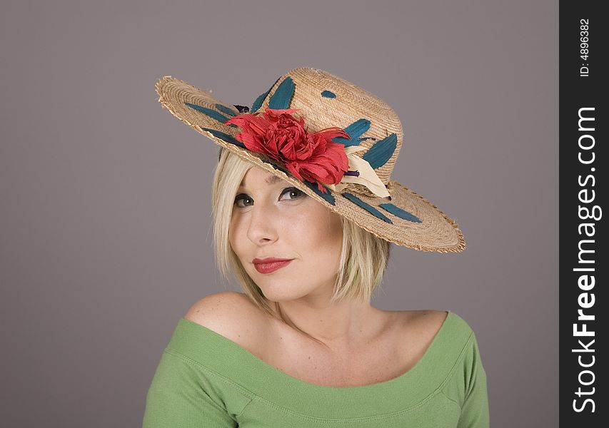 A blonde in a green blouse and a flowered hat slanted to one side. A blonde in a green blouse and a flowered hat slanted to one side