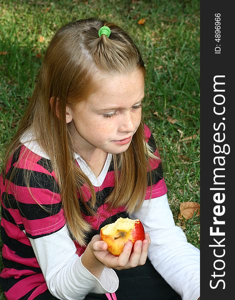 A white caucasian girl child holding a half eaten apple in her hand. A white caucasian girl child holding a half eaten apple in her hand