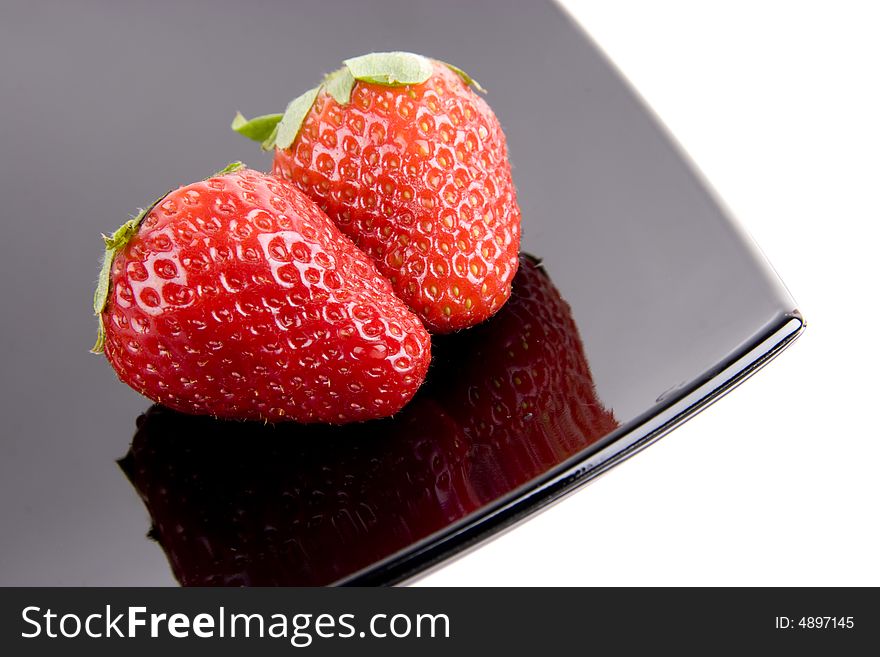 Five ripe strawberries on the black plate. Five ripe strawberries on the black plate