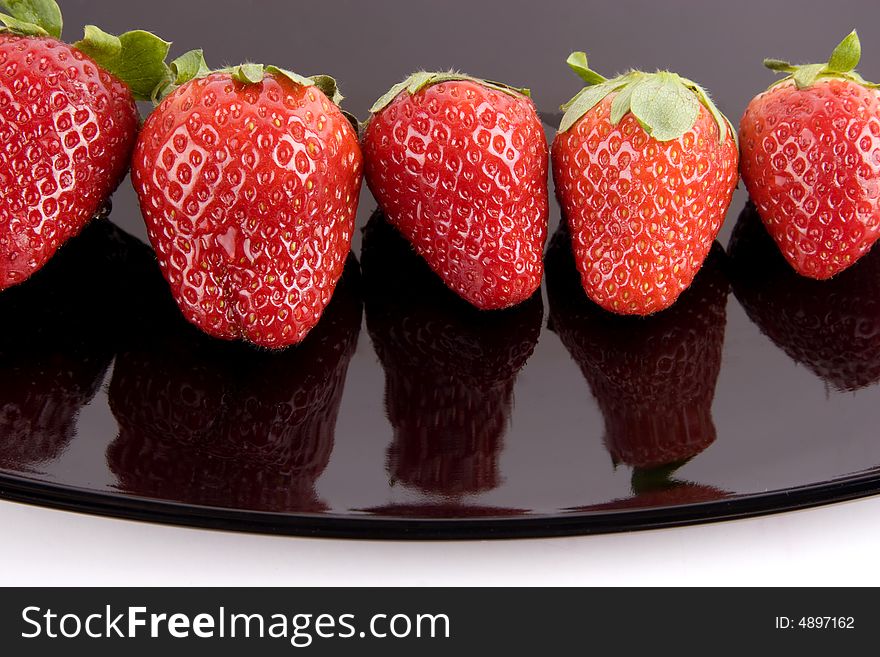 Five ripe strawberries on the black plate. Five ripe strawberries on the black plate