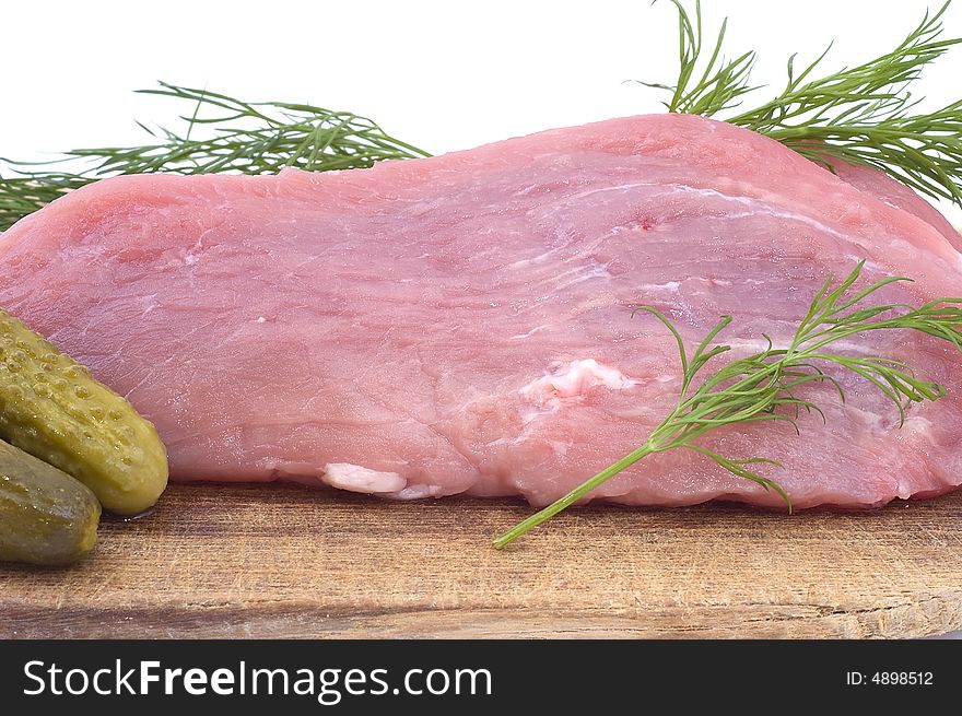 Raw pork schnitzel with pickled cucumbers and dill on a wooden hardboard isolated on white. Close-up